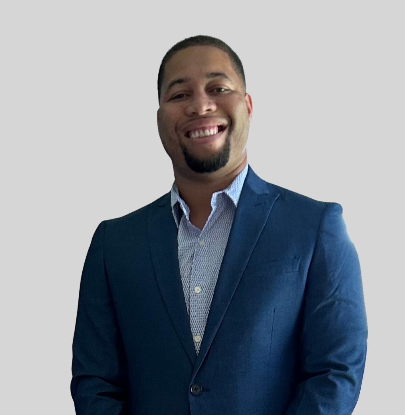 Smiling man in a blue blazer and light dress shirt, posing for a portrait against a gray background.